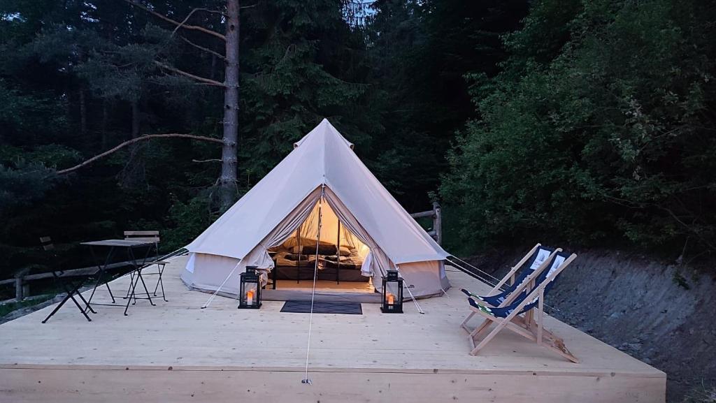 a white tent with a bed in it with two chairs at Glamping-Dimbo in Krynica Zdrój