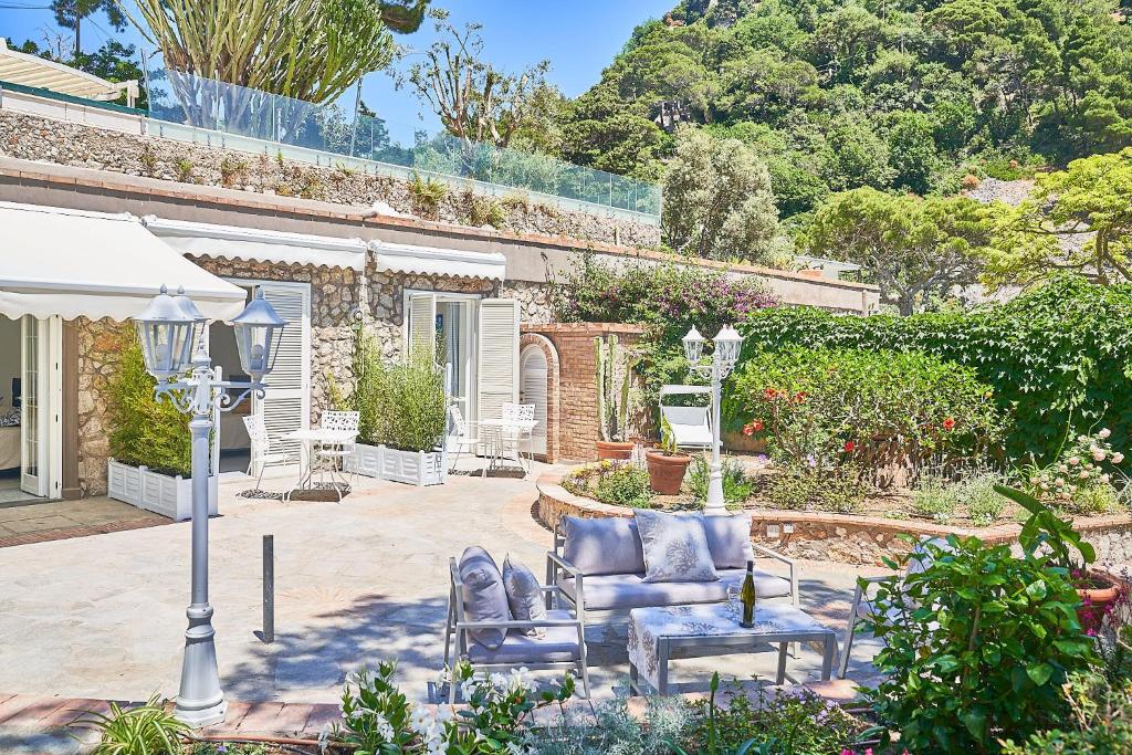 een patio met een bank, een stoel en een lamp bij To Be Capri Sea view Rooms in Capri