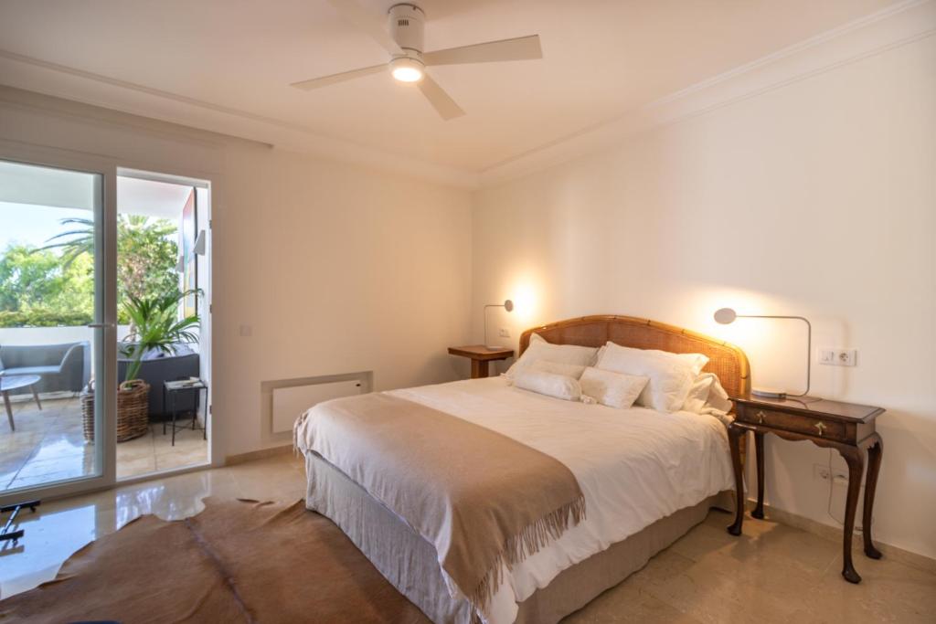 sypialnia z łóżkiem ze stołem i oknem w obiekcie Lujoso y moderno piso con piscina cerca del campo de golf en Guadalmina Alta Marbella - Quetzal 54 w Marbelli