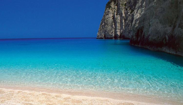 a beach with blue water and a cliff at Nikiana Family Apartment in Nikiana