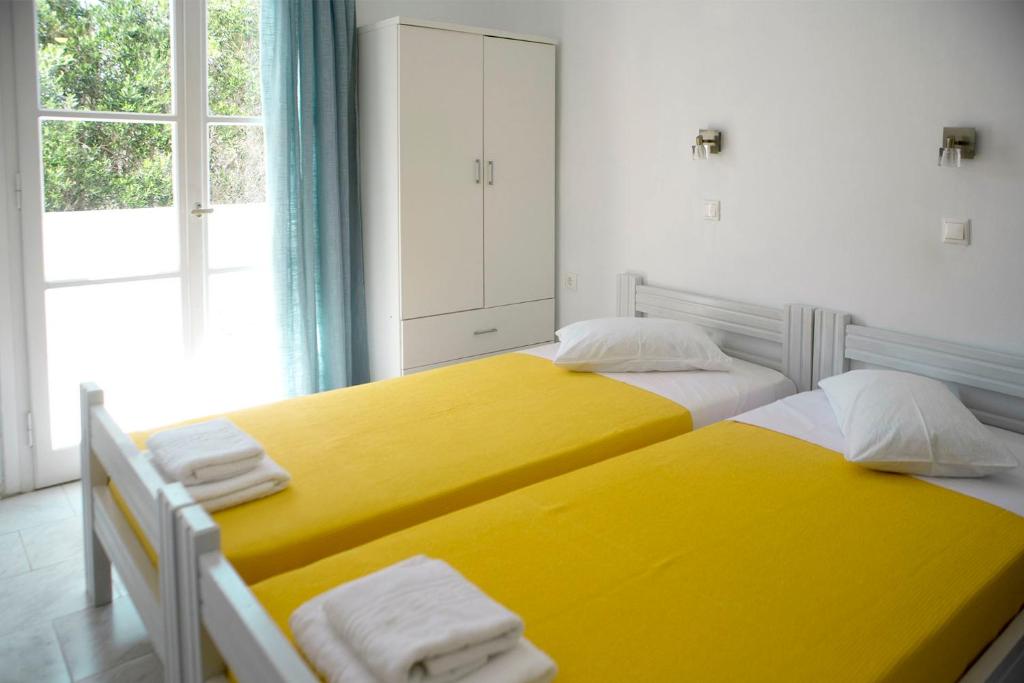 two yellow beds in a room with a window at Ios Penelope in Ios Chora