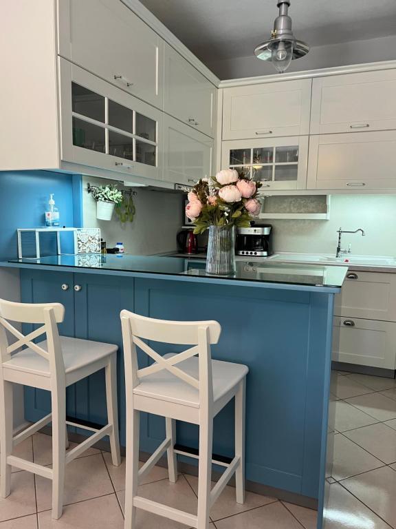 a blue kitchen with white cabinets and a vase of flowers at Sea Side Welcome Apartments in Perea