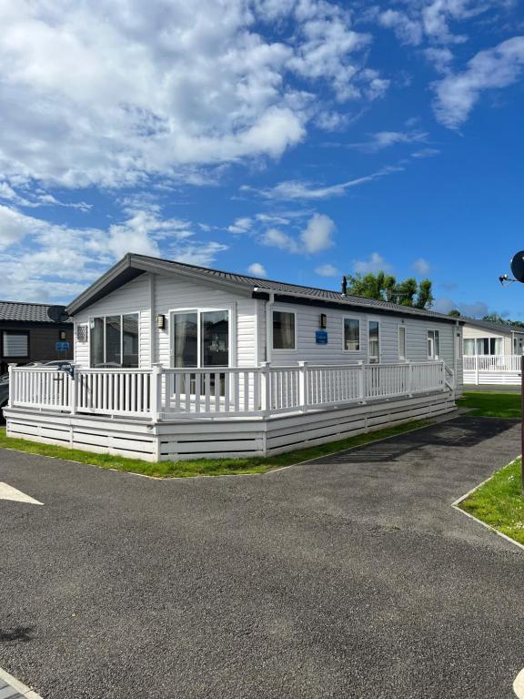 a white house with a white fence at Lodge Caravan on Holiday Park in Chichester