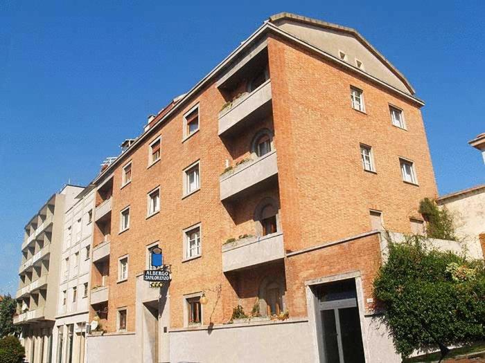 ein großes Backsteingebäude in einer Stadtstraße in der Unterkunft Albergo San Lorenzo in Grosseto