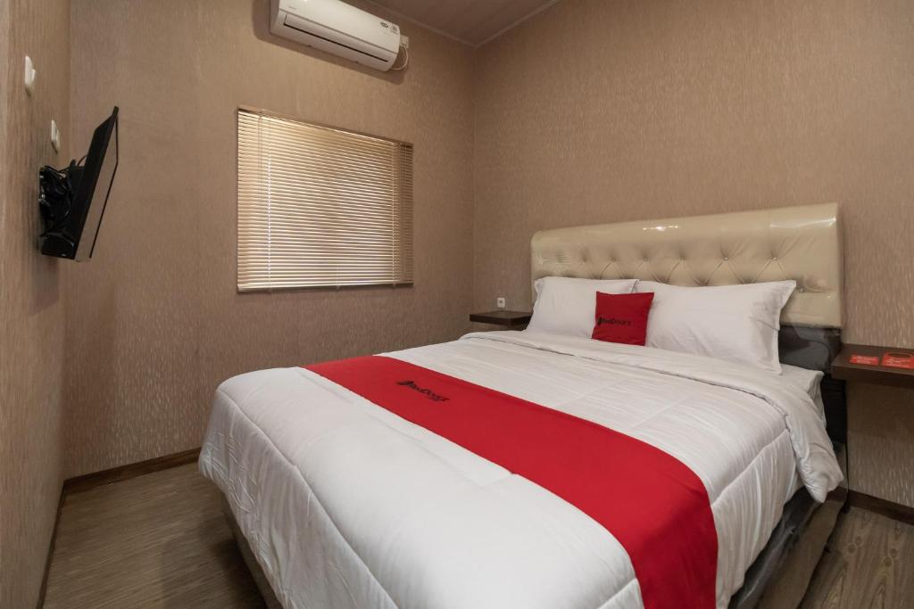 a bedroom with a large bed with a red blanket at RedDoorz @ Jalan Srikandi Pekanbaru in Parit