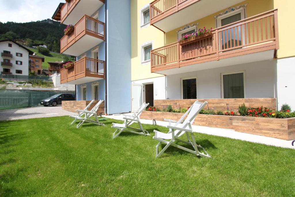 two lawn chairs sitting on the grass in front of a building at Residence Alpen Park in Molveno