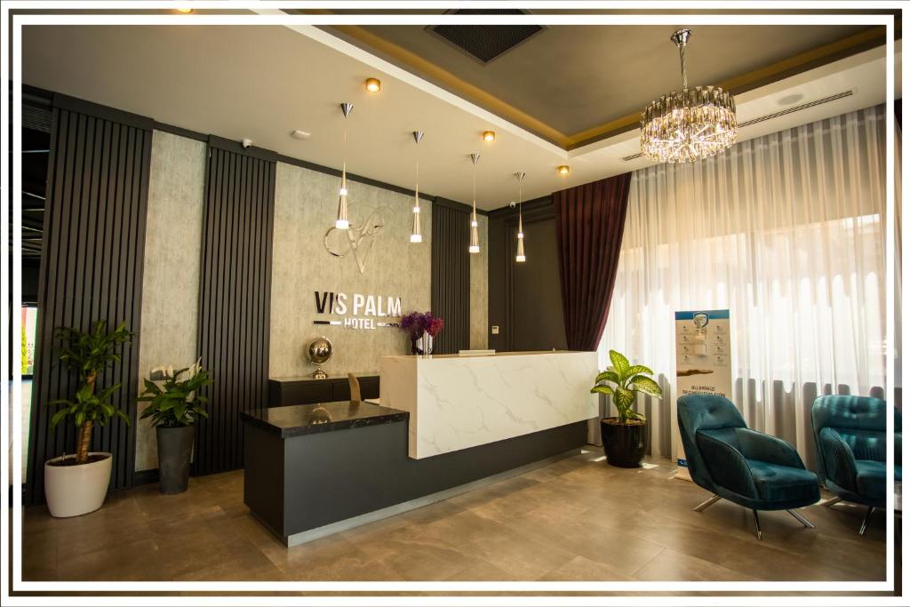a lobby with a reception desk and two blue chairs at VIS Palm Hotel Ganja in Ganja