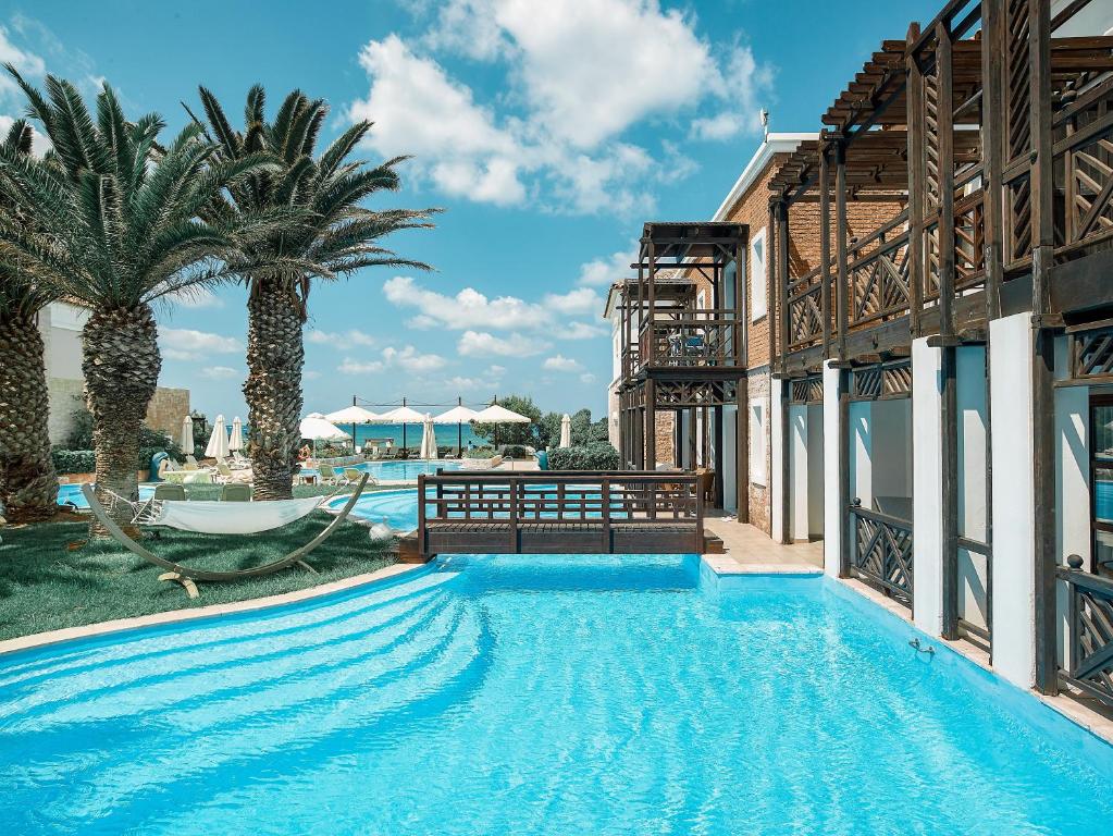 a swimming pool with palm trees and a resort at Mitsis Royal Mare in Hersonissos