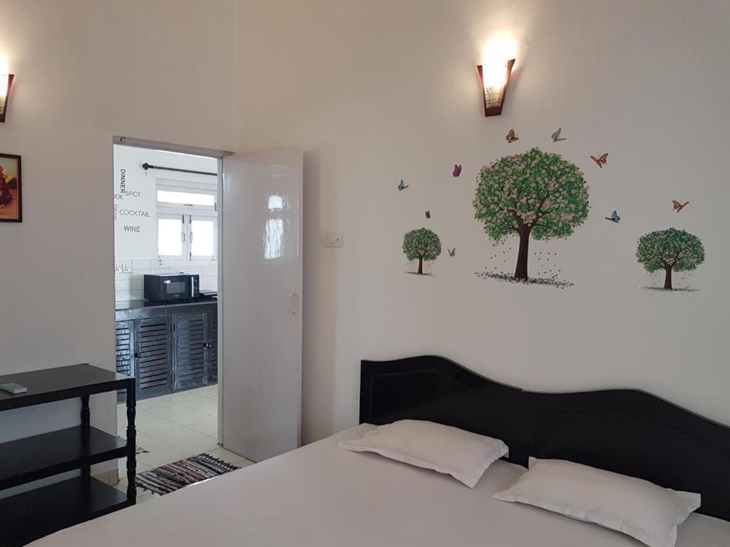 Schlafzimmer mit einem Bett mit Bäumen an der Wand in der Unterkunft ARY Royal Palms - 1 BHK in Benaulim