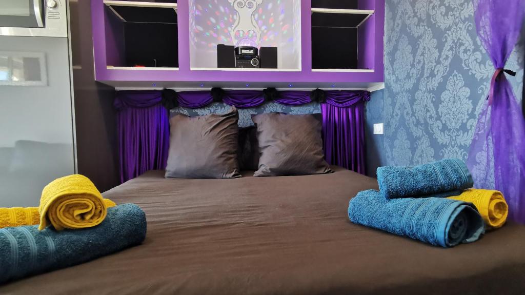 a bed with purple and blue pillows and purple curtains at Port Nature Village Naturiste in Cap d'Agde