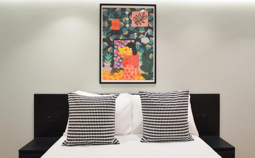 a bed with black and white pillows and a painting at Earls Court East Serviced Apartments by StayPrime in London