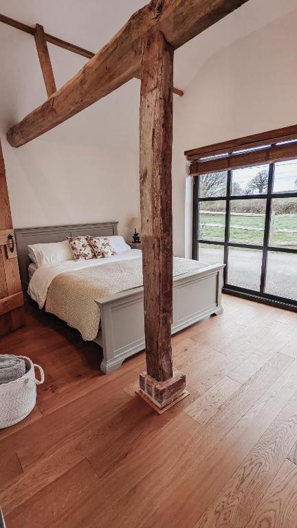 a bedroom with a bed and a large window at Bluebell Copse Cottages New Forest with Hot Tub in Southampton