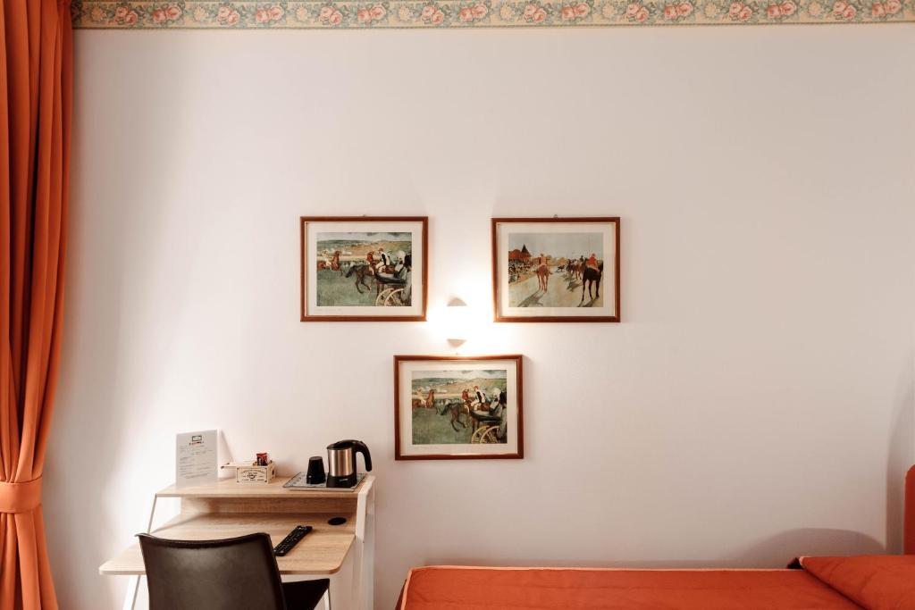 Pokój z biurkiem i 3 zdjęciami na ścianie w obiekcie Locanda Tradate w mieście Tradate