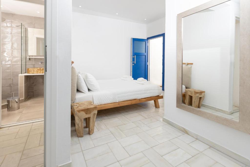 een witte kamer met een bed en een spiegel bij Andromeda Residence in Mykonos-stad