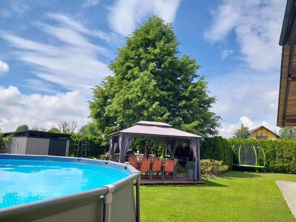 een prieel met een tafel en stoelen naast een zwembad bij Studio apartma Žirovnik in Cerklje na Gorenjskem