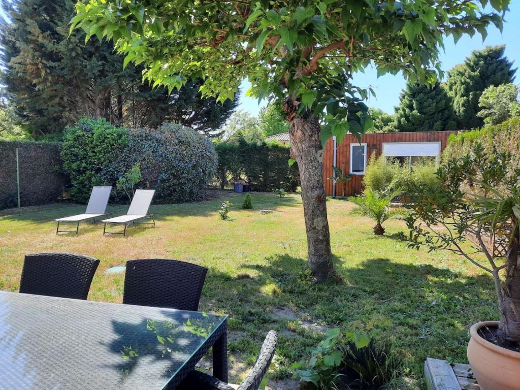 un jardin avec des chaises, une table et un arbre dans l'établissement MAISON DE PLAIN PIED Classée "MEUBLE DE TOURISME 4 ETOILES " ET CHALET INDEPENDANT, à Seignosse