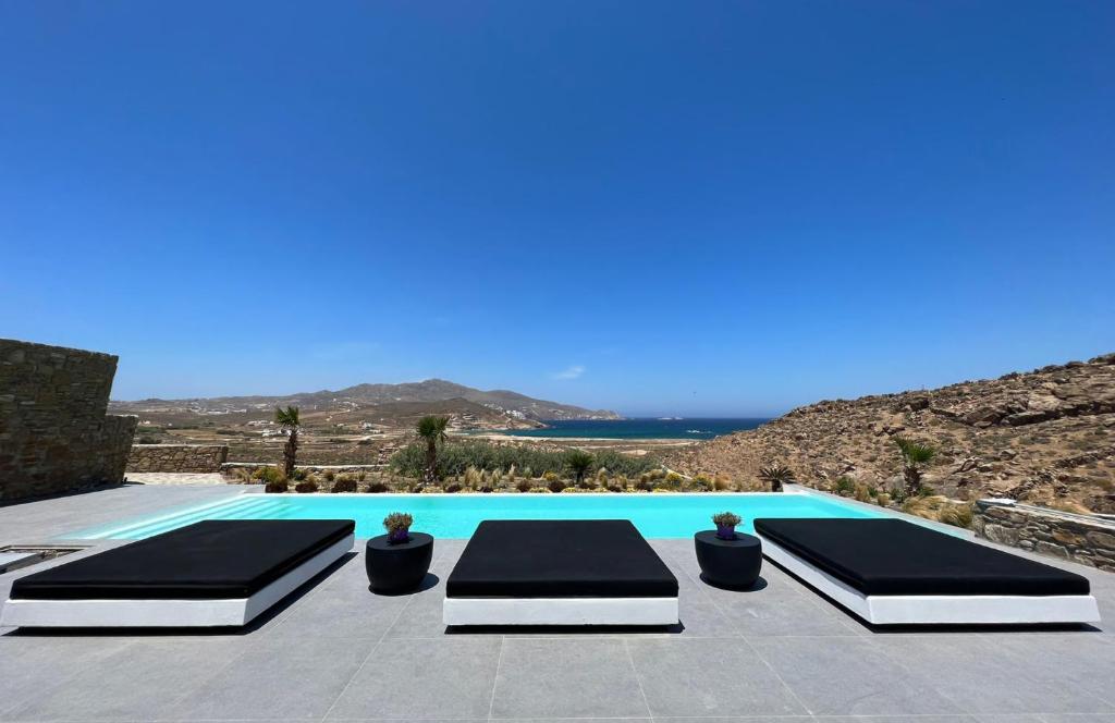 - une piscine avec 2 lits et une vue sur l'océan dans l'établissement BLACK AND WHITE VILLAS FTELIA - MYKONOS, à Mykonos