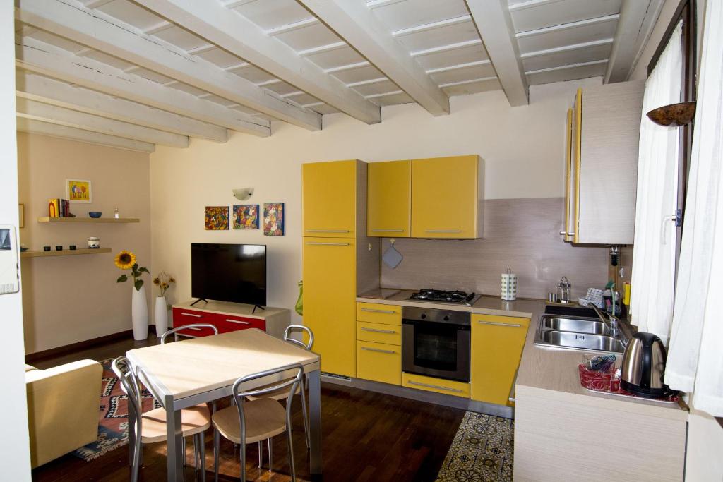eine Küche mit gelben Schränken und einem Tisch in der Unterkunft Residence dei Frutti pieno centro - Il Ribes in Padua