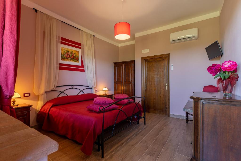 a bedroom with a bed with red sheets and pink pillows at B&B FONTERONCONE di KRYVUTA OKSANA in Montepulciano