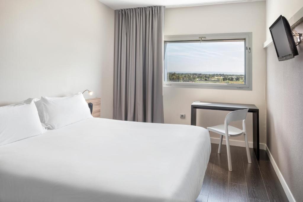 a hotel room with a bed and a desk and a window at B&B HOTEL Albacete in Albacete