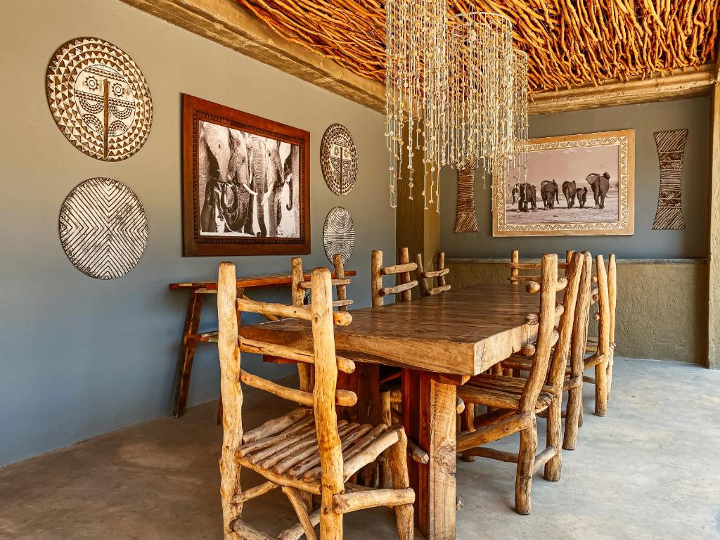 uma sala de jantar com uma mesa de madeira e cadeiras em Gwango Heritage Resort em Dete