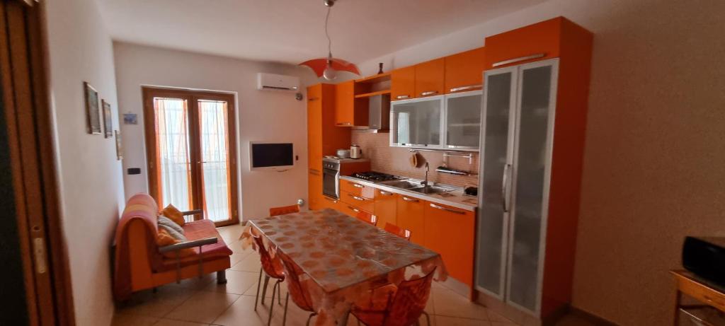 una cocina con armarios naranjas y una mesa. en Casa Marco, en Praia a Mare