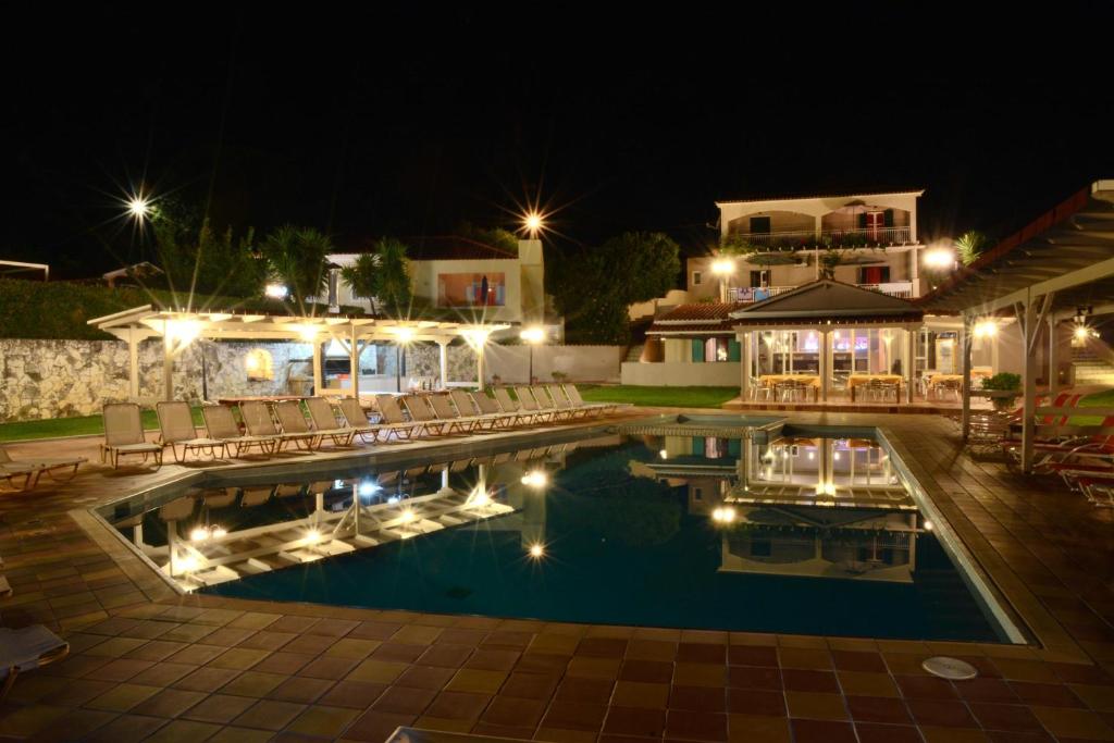 a swimming pool with chairs and a house at night at Residence Poseidon in Spartia