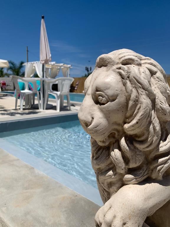 una statua di leone accanto alla piscina di Case Vacanza Zeus a Trappeto