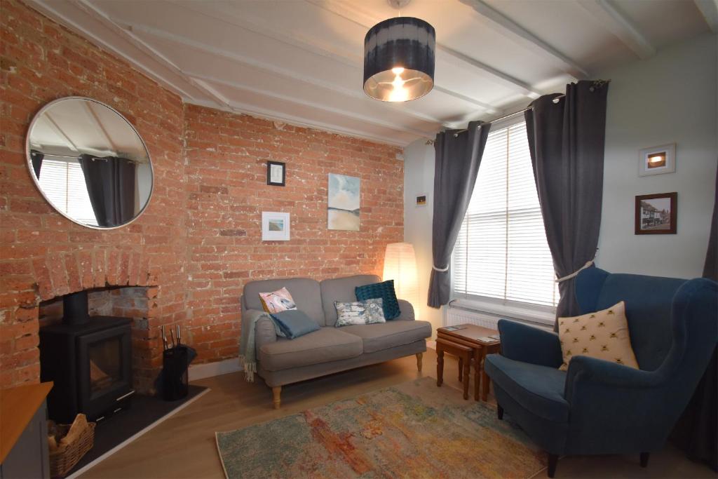 - un salon avec un canapé et un mur en briques dans l'établissement Honey Cottage, à Rye