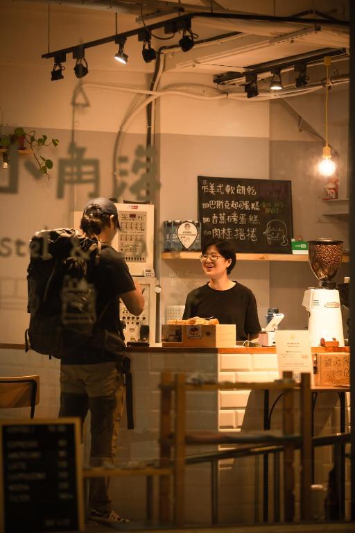 台北市にあるCorner Hostel &amp; Cafeのカウンターに立つバックパックの男