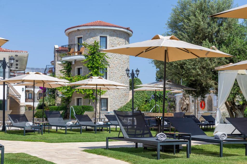 eine Gruppe von Stühlen und Sonnenschirmen vor einem Gebäude in der Unterkunft Orcey Hotel in Datca