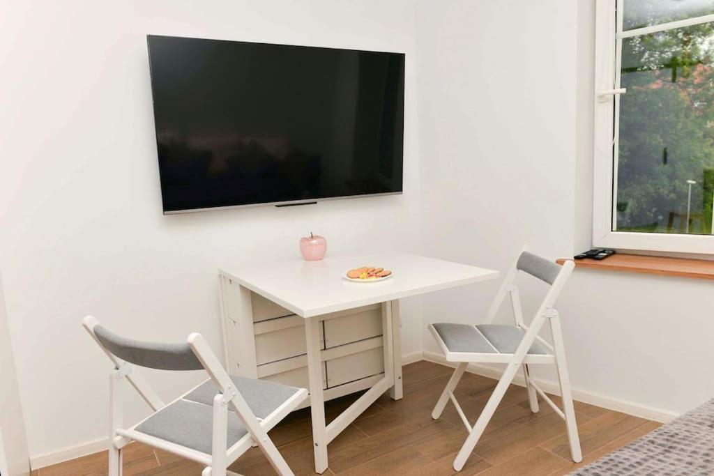 une table blanche et des chaises avec une télévision sur un mur dans l'établissement Apartament przy deptaku i Parku Zdrojowym - Polanica Zdrój, à Polanica-Zdrój