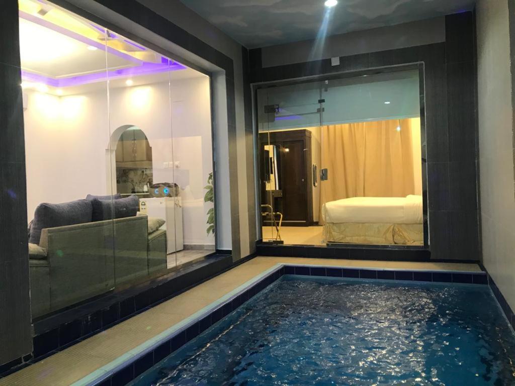 una piscina in una stanza con divano e una camera da letto di شاليهات رميس للعائلات RAMIS Chalet a Abha