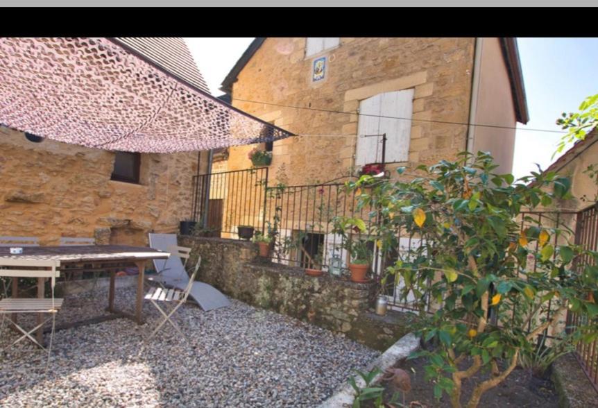 un patio avec une table et des chaises et un bâtiment dans l'établissement La Maison des Roches 4-6 personnes avec terrasse, à Sarlat-la-Canéda