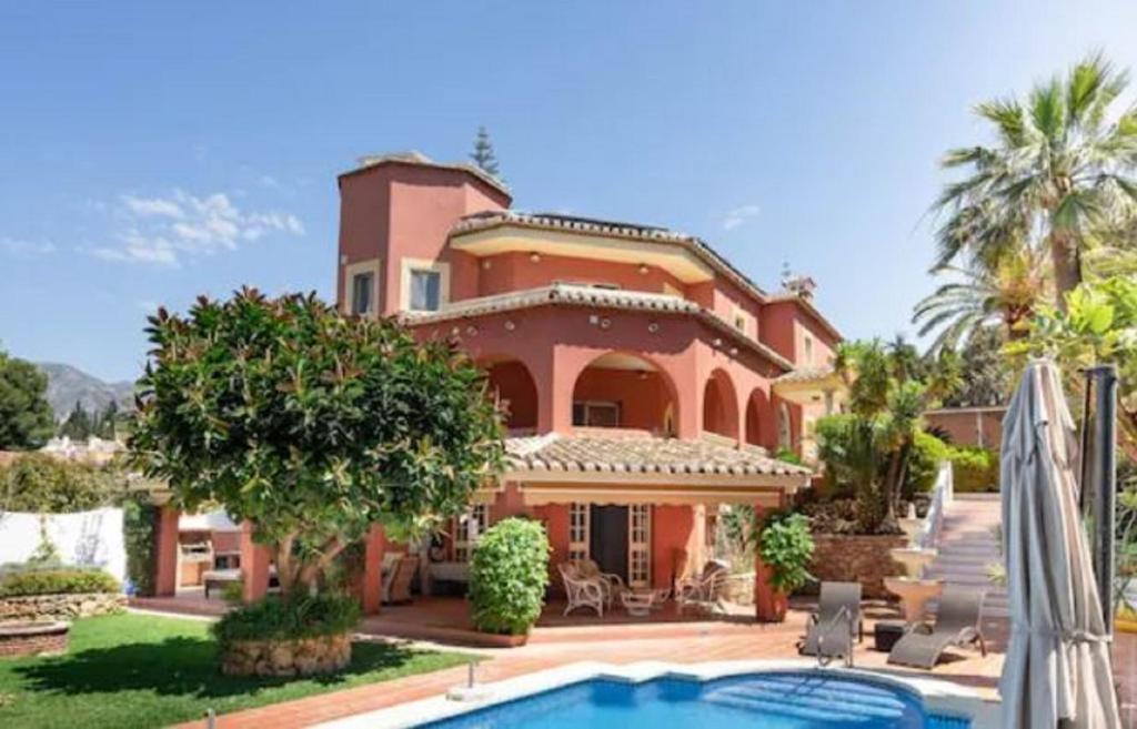 una casa grande con piscina frente a ella en Beautiful modern 4 bedroom villa with heated pool and cinema in Las Lagunas de Mijas, en Santa Fe de los Boliches