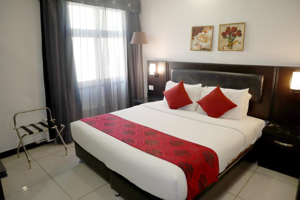 a hotel room with a large bed with red pillows at Easy Inn Hotel Suites in Amman