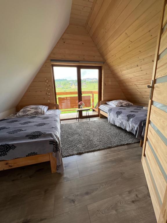 two beds in a room with a large window at Domki Na Stoku in Czarna Góra