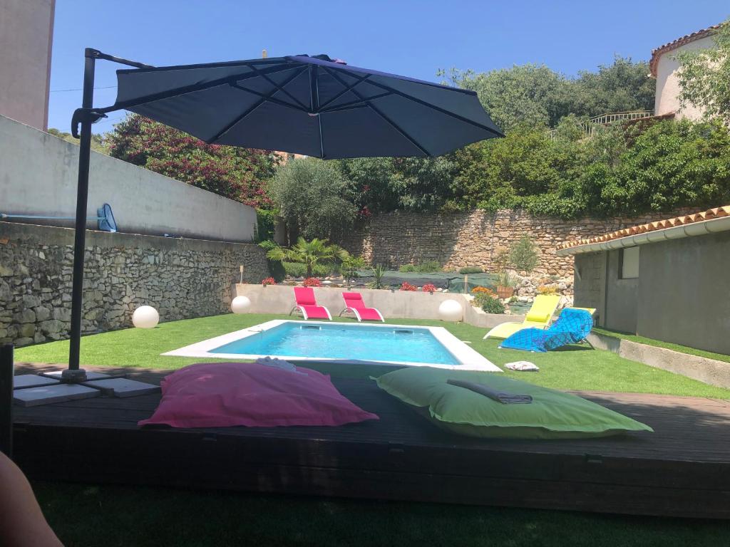 a pool with an umbrella and some chairs and a pool at Villa calme avec piscine privée nimes in Nîmes