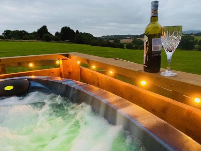 a bottle of wine and a glass next to a hot tub at Burtree Country House and Retreats Tipi in Thirkleby