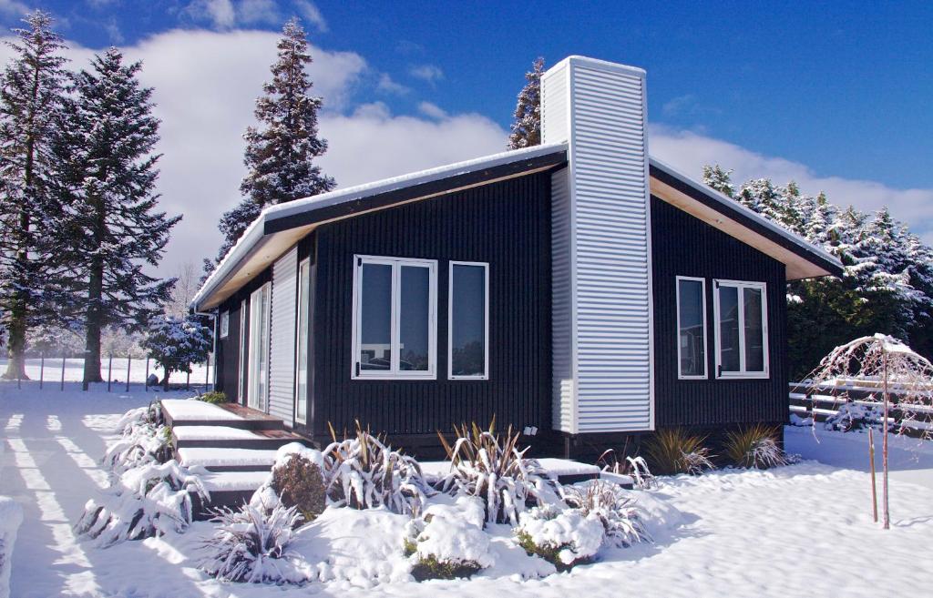 uma pequena casa preta com neve no chão em Handbridge - Ohakune Holiday House em Ohakune