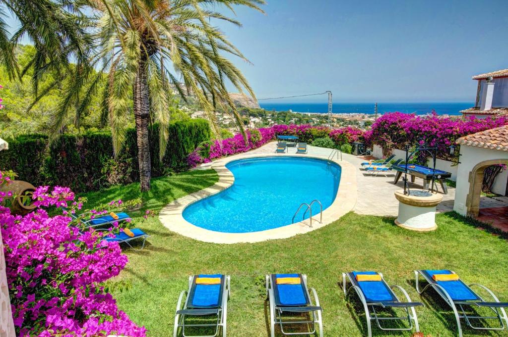 un patio trasero con piscina, sillas y el océano en Villa Cau by Villa Plus, en Jávea