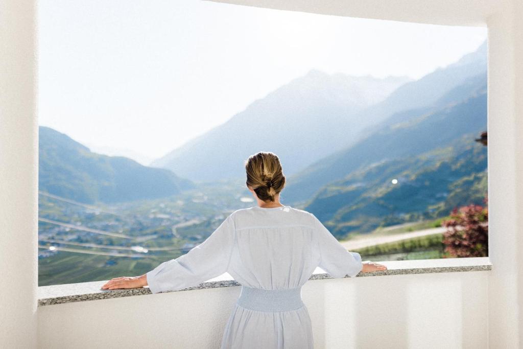 a woman standing on a ledge looking out at the mountains at Hotel Paradies in Tirolo
