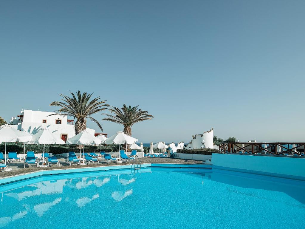 a large swimming pool with chairs and umbrellas at Mitsis Cretan Village in Hersonissos