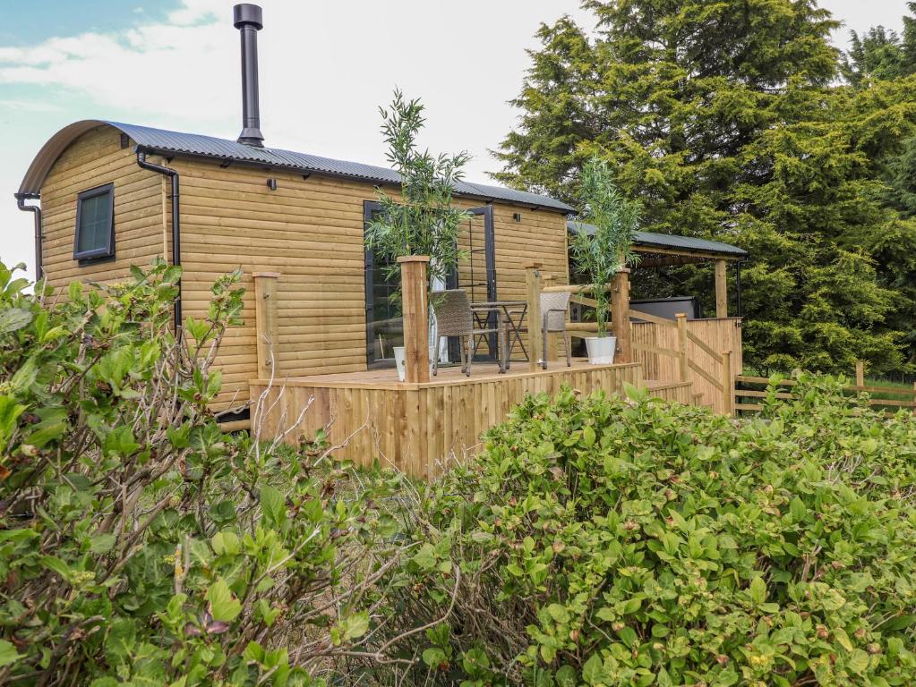 een houten hut met een terras met een tafel en stoelen bij High Rigg Shepherd's Sunrise in Brampton