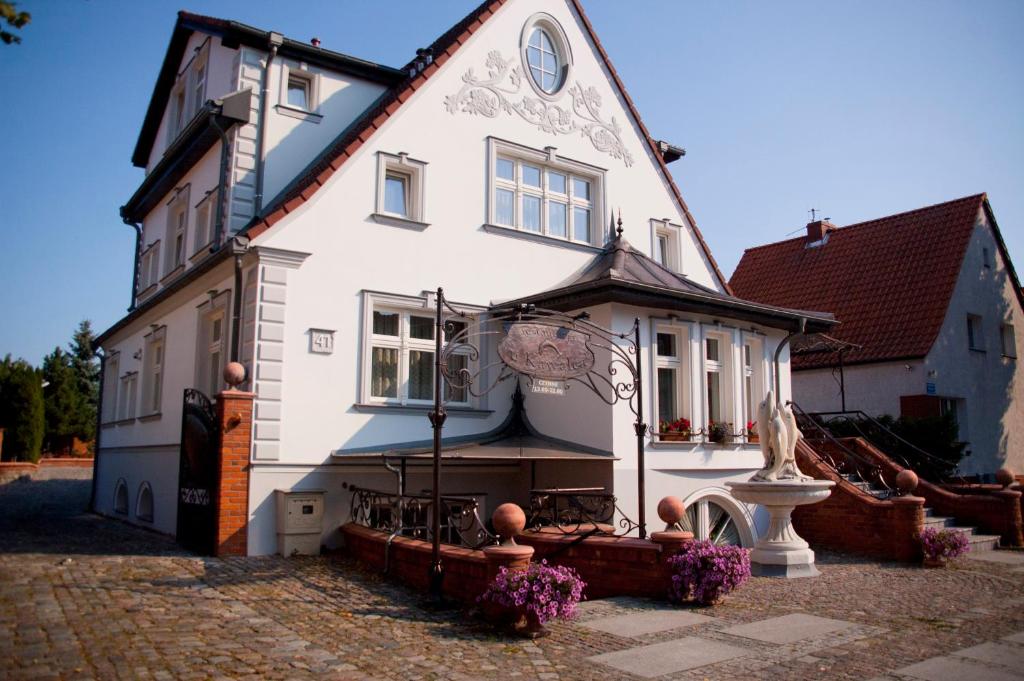 une grande maison blanche avec des fleurs devant elle dans l'établissement Noclegi U Kawalca, à Szczecinek