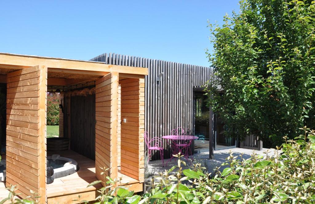 un edificio in legno con un tavolo e un albero di La Parenthèse a Bergerac