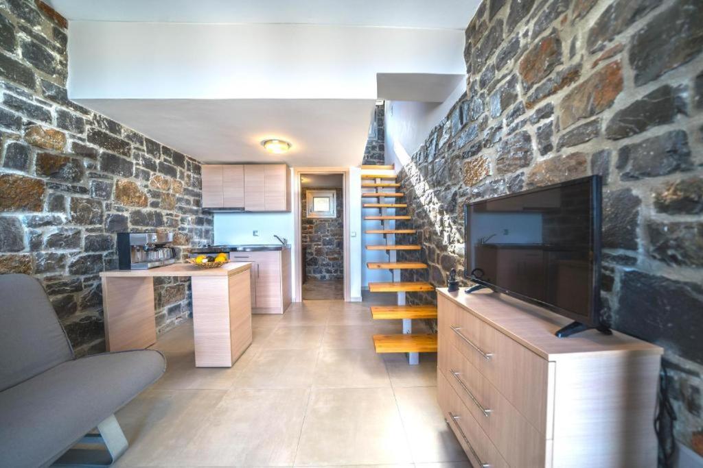 salon ze schodami i kamienną ścianą w obiekcie TerraZeus - Stone House Beachfront 1 w mieście Milatos
