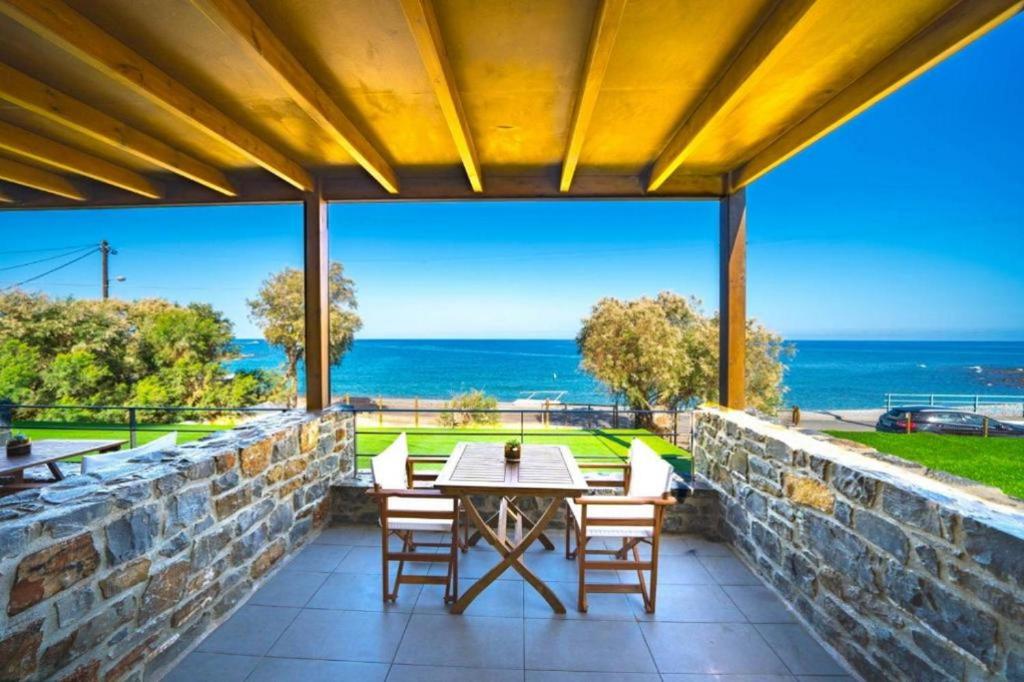 taras ze stołem i krzesłami i widokiem na ocean w obiekcie TerraZeus - Stone House Beachfront 1 w mieście Milatos