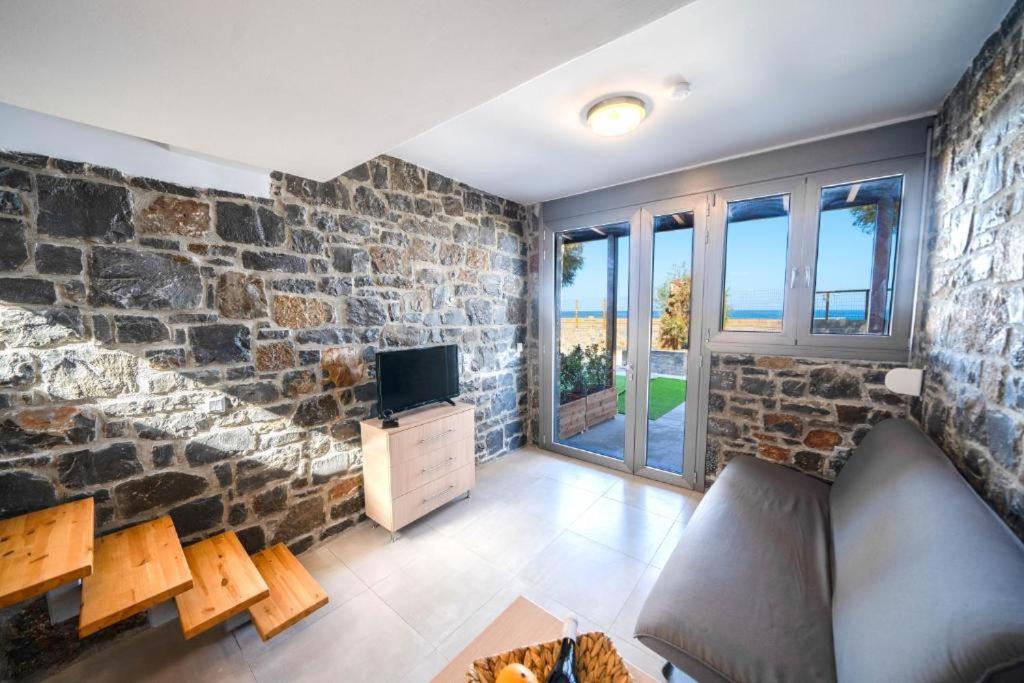 salon z kamienną ścianą i telewizorem w obiekcie TerraZeus - Stone House Beachfront 1 w mieście Milatos