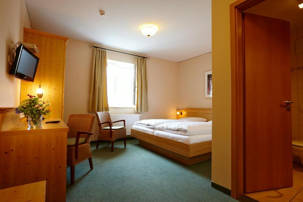 um quarto de hotel com uma cama e uma televisão em Hotel Eberl em Hattenhofen